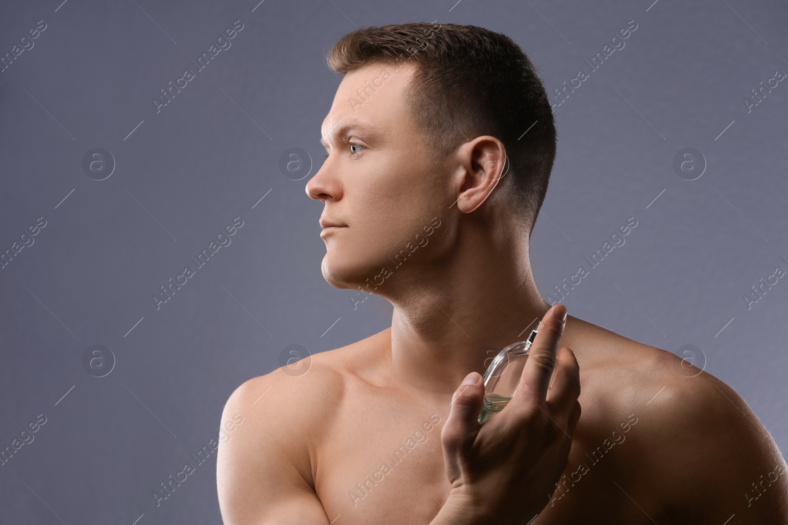 Photo of Handsome man using perfume on grey background