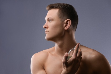 Handsome man using perfume on grey background