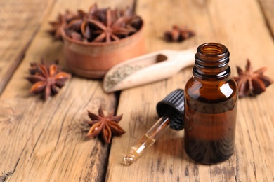 Photo of Bottle of essential oil, dropper and anise on wooden table. Space for text