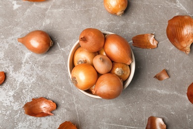 Bowl with fresh ripe onions on table, top view