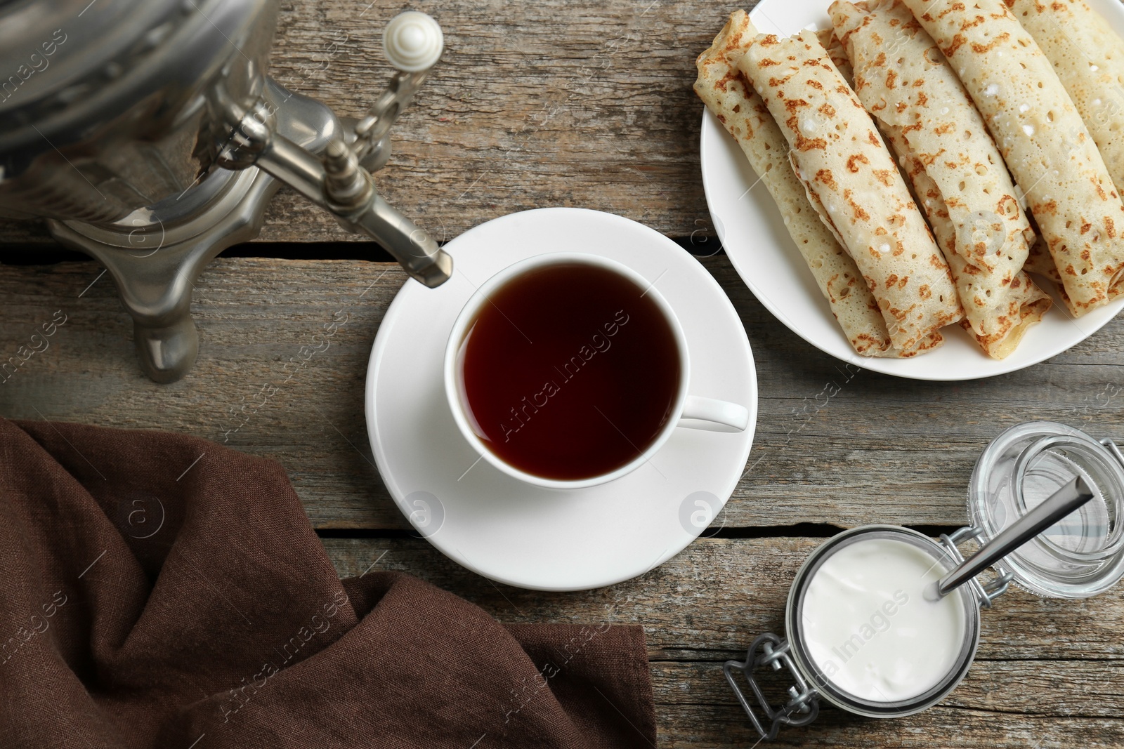 Photo of Vintage samovar, cup of hot drink and pancakes served on wooden table, flat lay. Traditional Russian tea ceremony