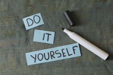 Photo of Phrase Do It Yourself and marker on grey wooden table, flat lay. DIY concept