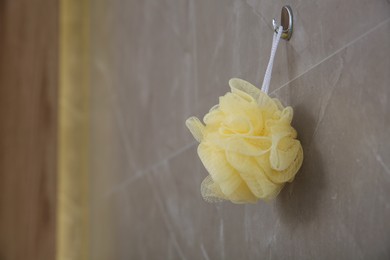 Photo of Yellow sponge hanging on grey wall in bathroom