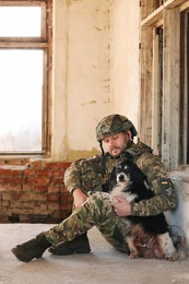 Ukrainian soldier sitting with stray dog in abandoned building