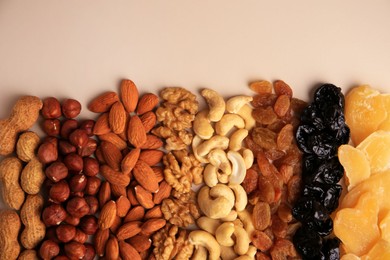 Mix of delicious dried nuts and fruits on beige background, flat lay