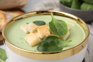 Photo of Delicious spinach cream soup with croutons in bowl on table, closeup