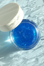 Open jar of cosmetic product on light blue background, top view