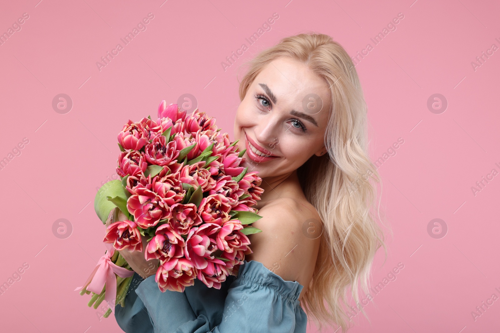 Photo of Happy young woman with beautiful bouquet on dusty pink background