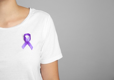 Woman with purple ribbon on grey background, closeup with space for text. Domestic violence awareness