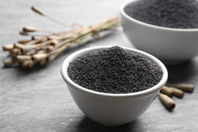 Photo of Poppy seeds in bowl on grey table