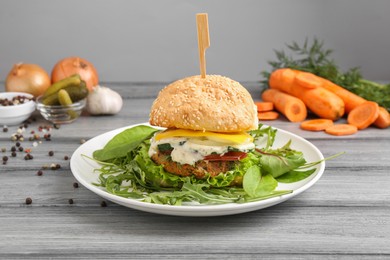 Photo of Delicious vegetarian burger served on grey wooden table