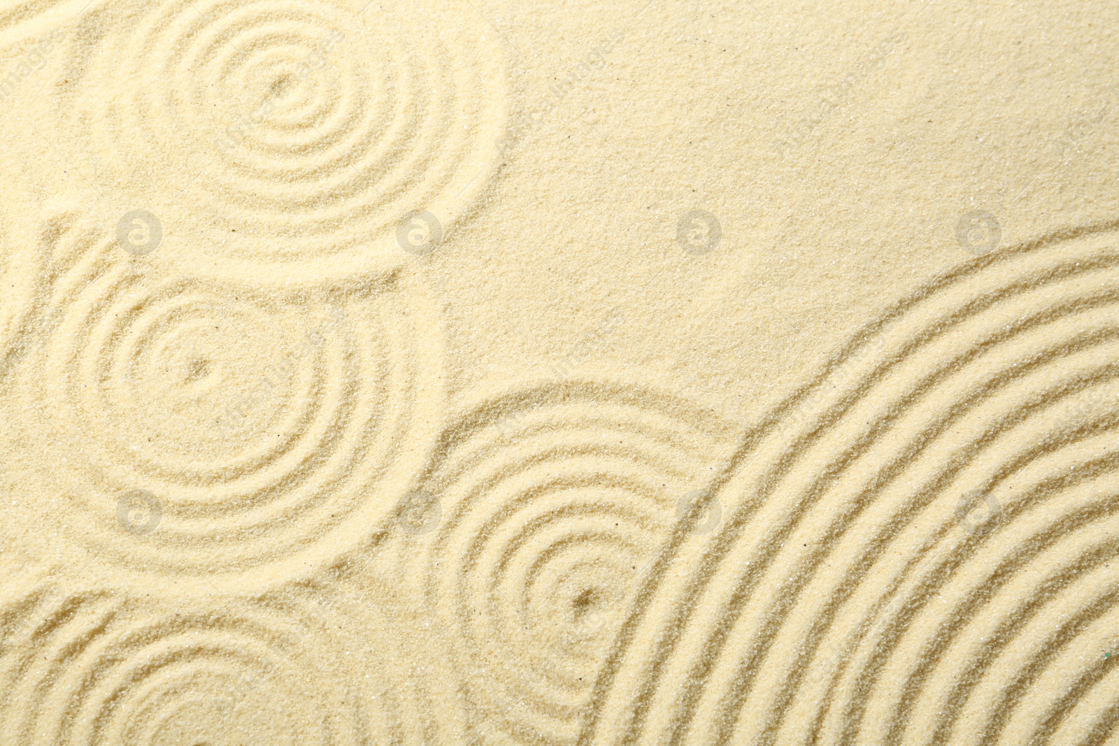 Photo of Zen rock garden. Circle patterns on beige sand, top view