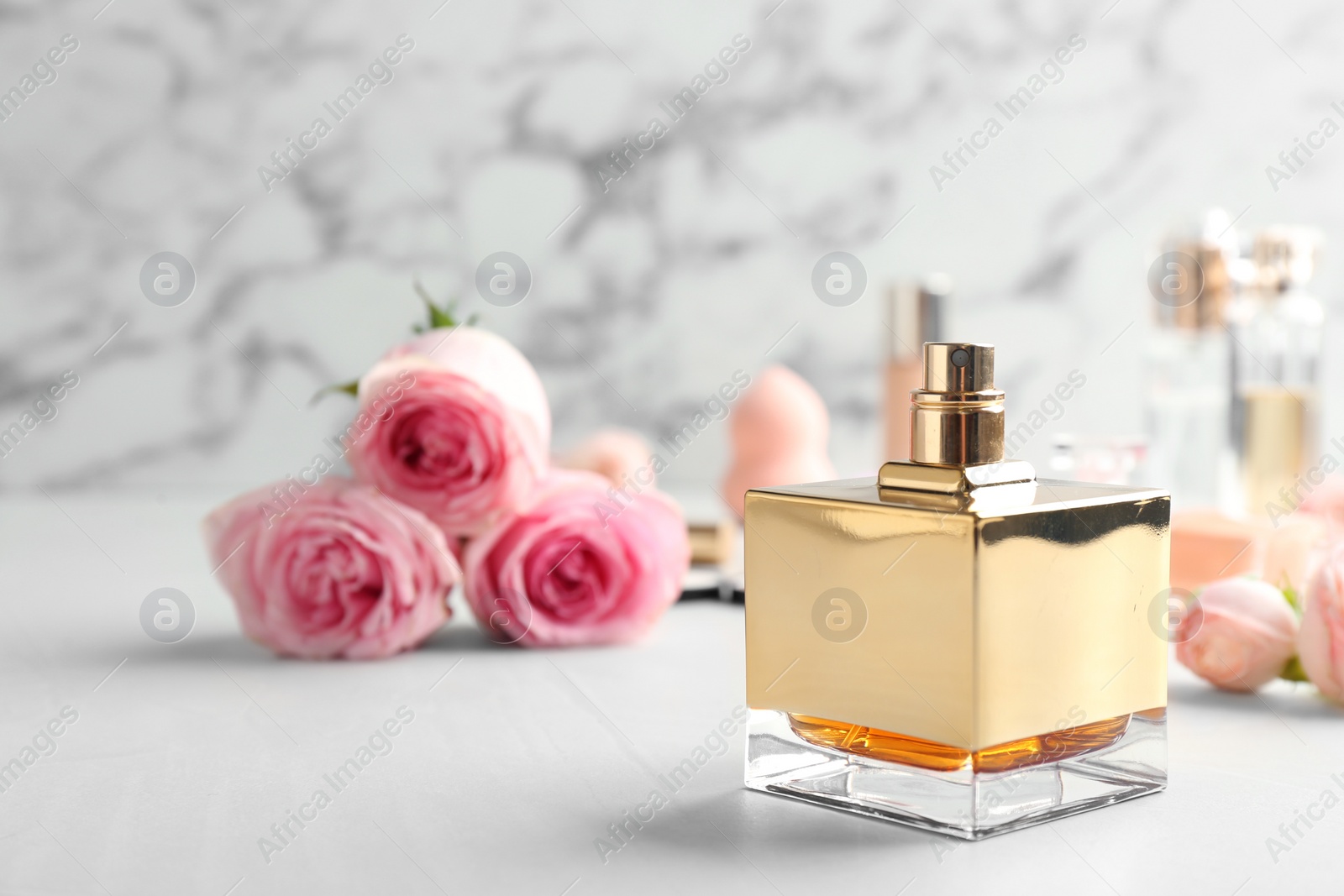 Photo of Bottle of perfume and roses on table against marble background. Space for text