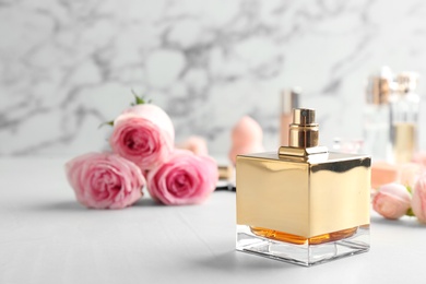 Photo of Bottle of perfume and roses on table against marble background. Space for text