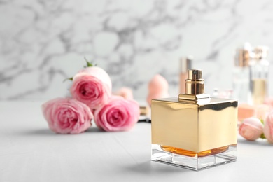 Bottle of perfume and roses on table against marble background. Space for text