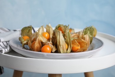 Photo of Ripe physalis fruits with dry husk on white table