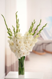 Photo of Vase with beautiful white gladiolus flowers on wooden table in room, space for text