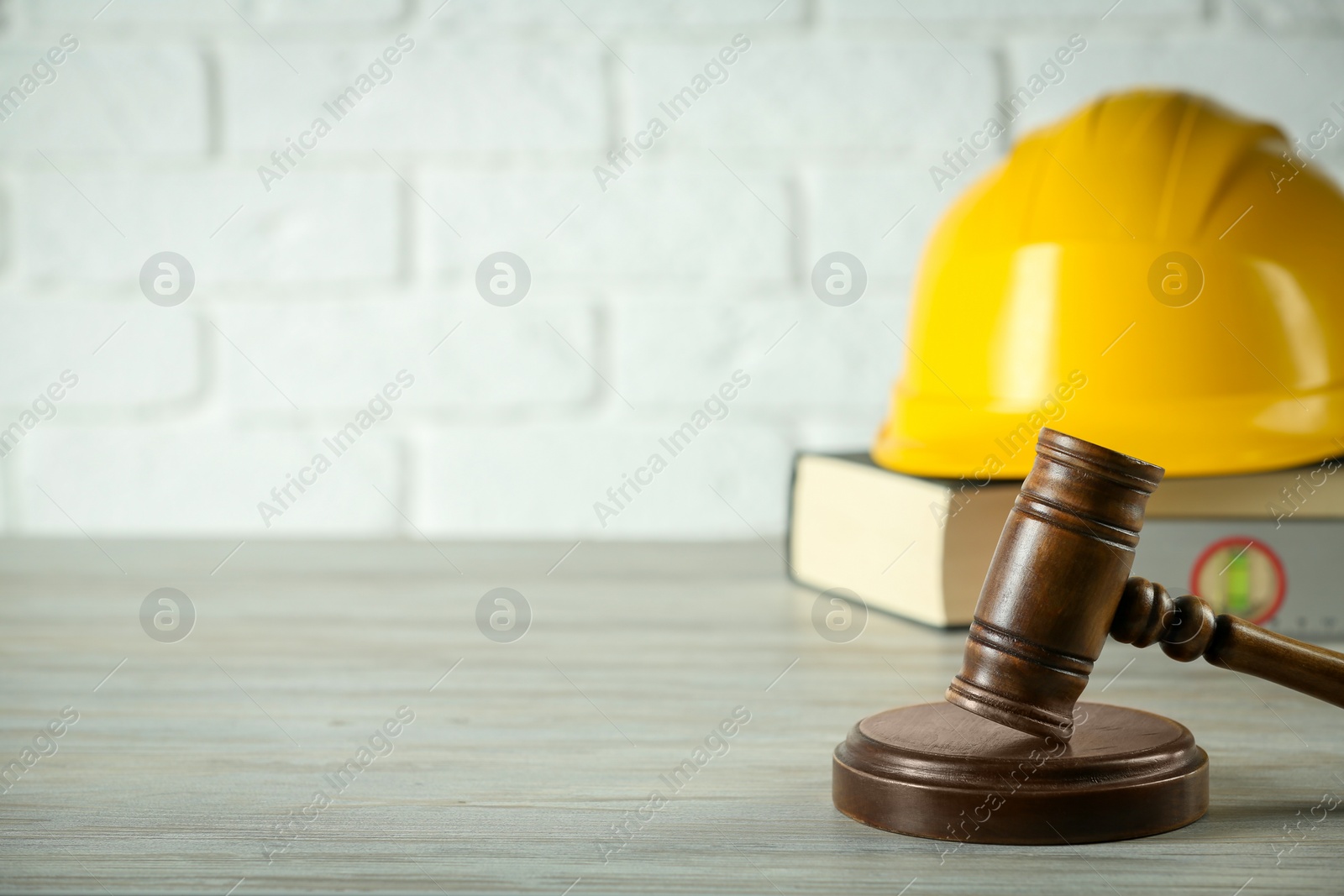 Photo of Construction and land law concepts. Judge gavel, protective helmet, ruler with book on wooden table, space for text