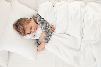 Photo of Cute boy sleeping in bed, above view