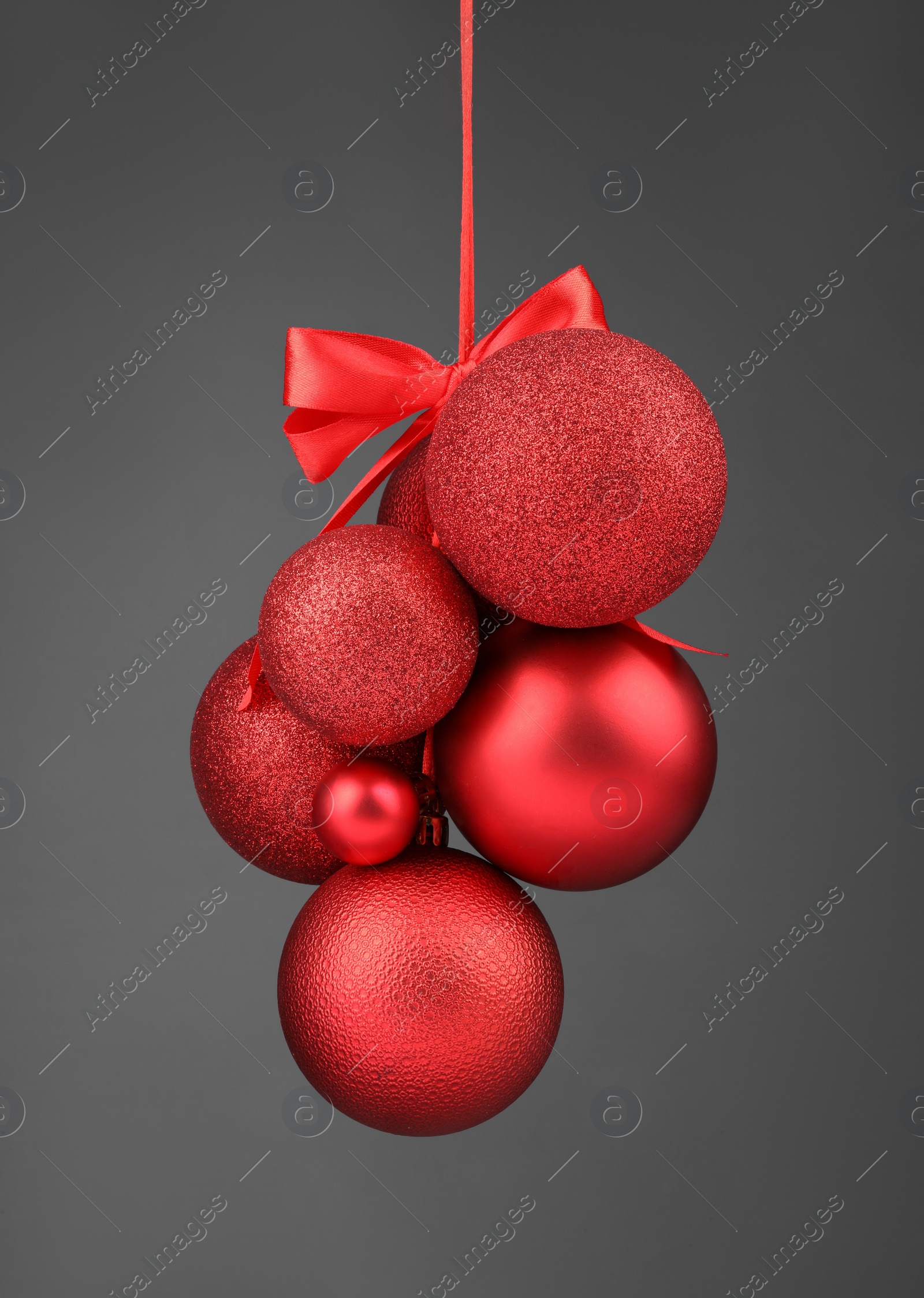 Photo of Beautiful red Christmas balls with bow on grey background