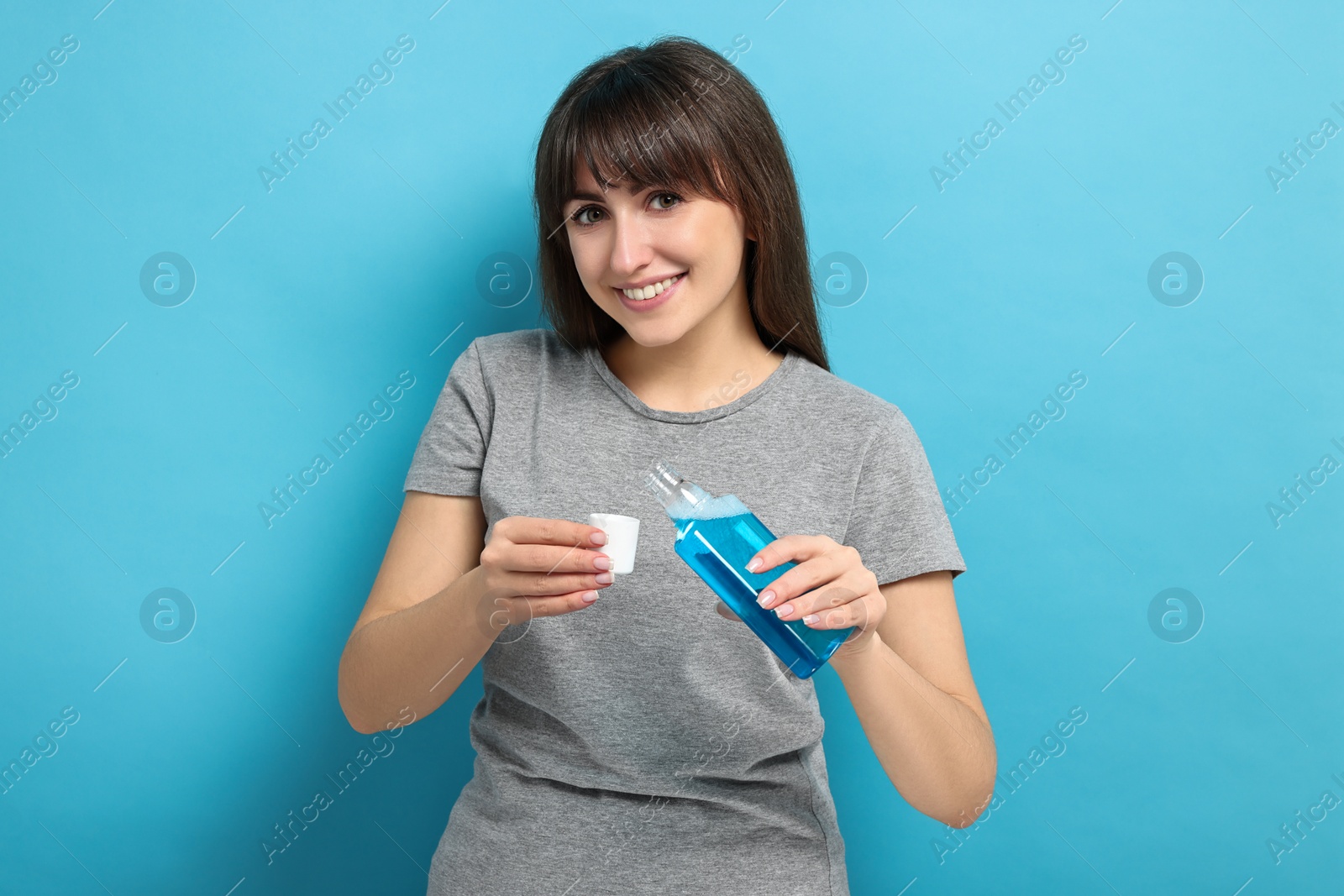 Photo of Young woman using mouthwash on light blue background