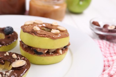 Photo of Fresh apples with nut butters and peanuts on plate, closeup