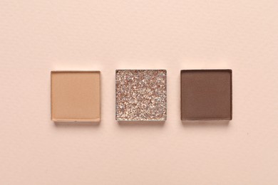 Different beautiful eye shadows on beige background, flat lay