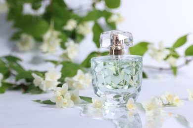 Photo of Aromatic perfume in bottle and beautiful jasmine flowers on white background