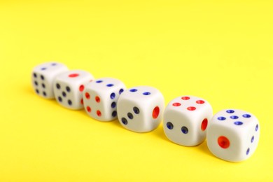 Photo of Many white game dices on yellow background, closeup