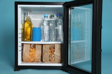 Photo of Mini bar filled with food and drinks on turquoise background, closeup