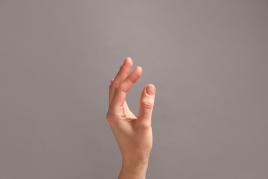 Photo of Woman holding something in hand on grey background, closeup