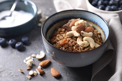 Photo of Tasty granola with nuts in bowl on gray table, closeup