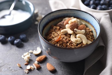 Tasty granola with nuts in bowl on gray table, closeup