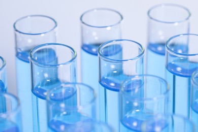 Photo of Test tubes with reagents on light blue background, closeup. Laboratory analysis