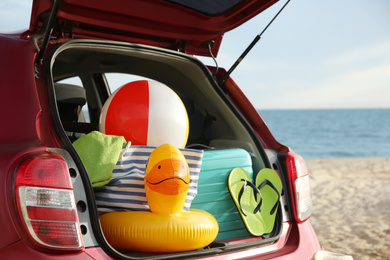 Photo of Red car with luggage on beach, closeup. Summer vacation trip