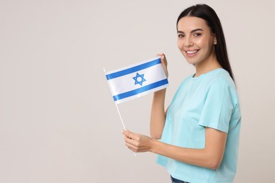 Photo of Happy young woman with flag of Israel on beige background, space for text