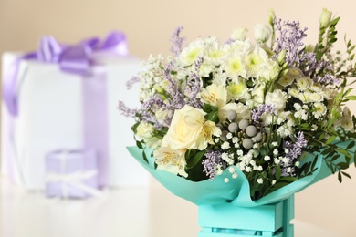 Photo of Beautiful bouquet of flowers and blurred gifts on background, closeup. Space for text