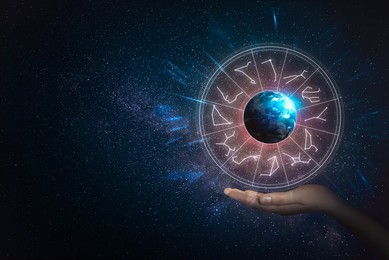 Image of Woman holding illustration of Earth with zodiac wheel around it in open space, closeup