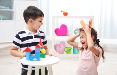 Photo of Cute children playing with colorful blocks at home