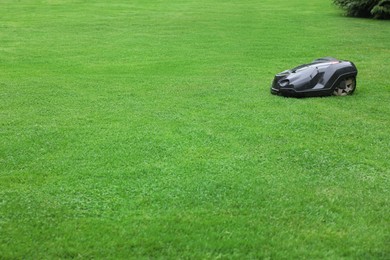 Photo of Modern lawn mower on green grass outdoors. Space for text