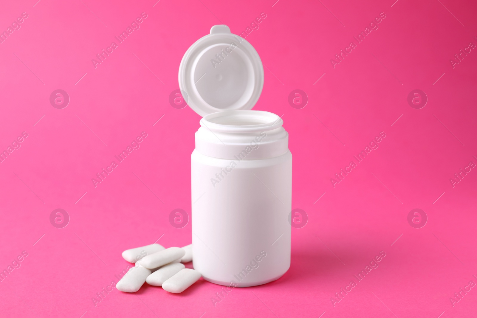 Photo of Jar with chewing gums on pink background