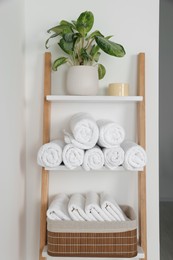 Photo of Soft towels on decorative ladder near white wall