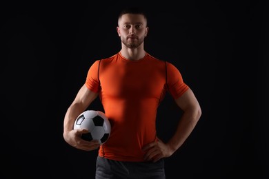 Photo of Athletic young man with soccer ball on black background