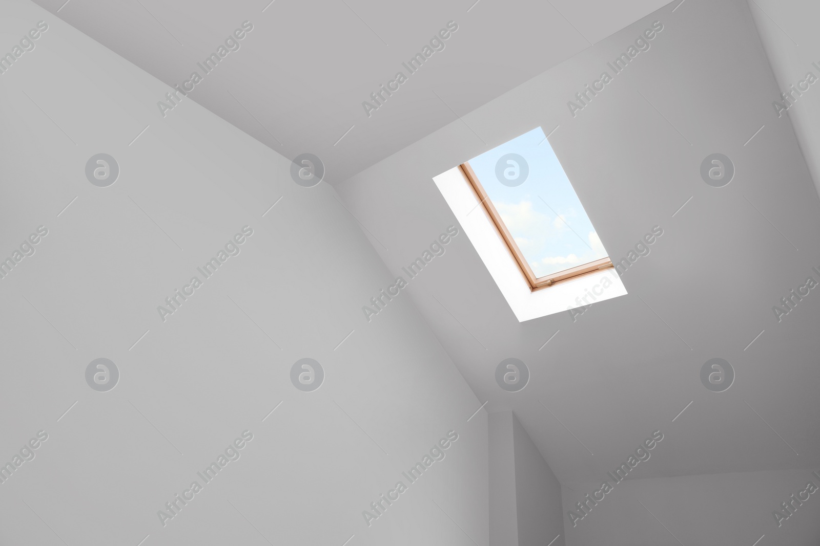 Photo of Skylight roof window and lamps on slanted ceiling in attic room, low angle view