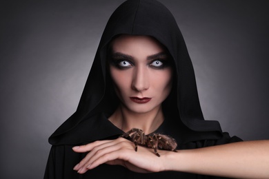 Mysterious witch with spooky spider on dark background