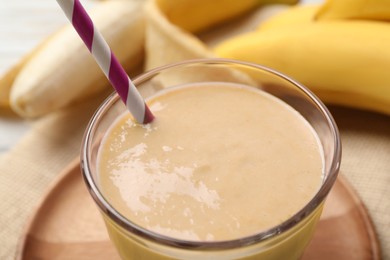 Photo of Glass of tasty banana smoothie with straw, closeup
