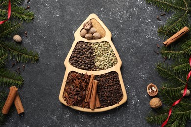 Different spices, nuts and fir branches on dark gray textured table, flat lay