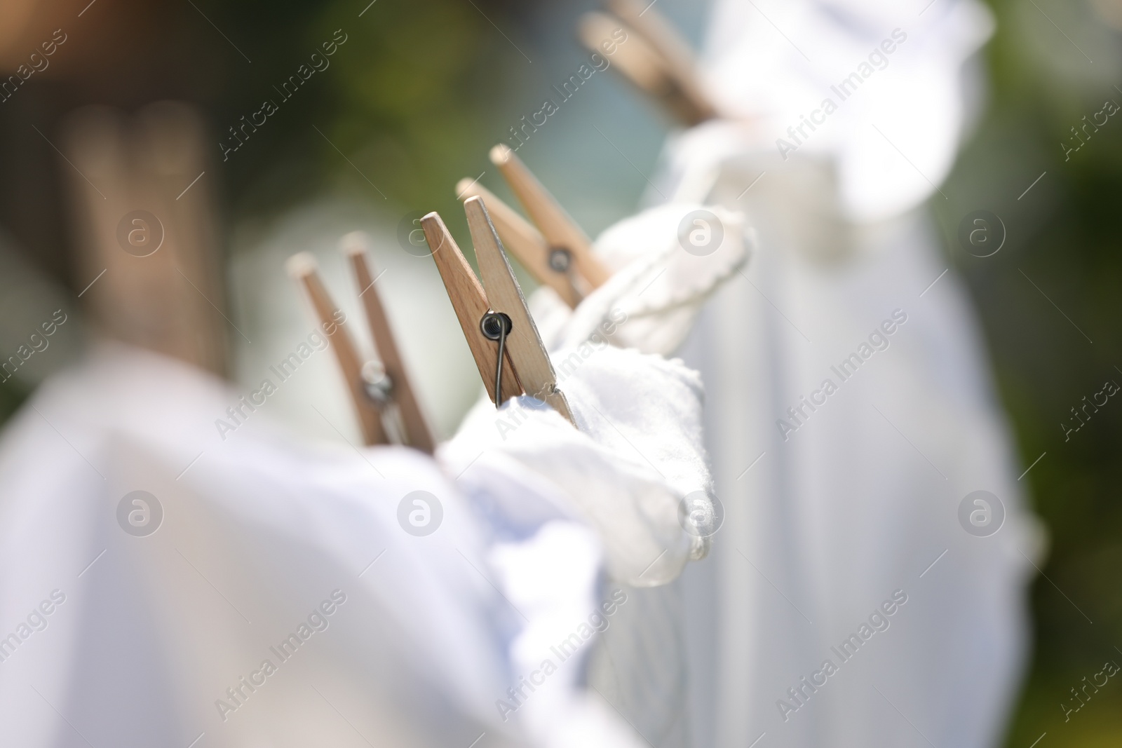 Photo of Clean clothes drying outdoors, closeup. Focus on clothespin