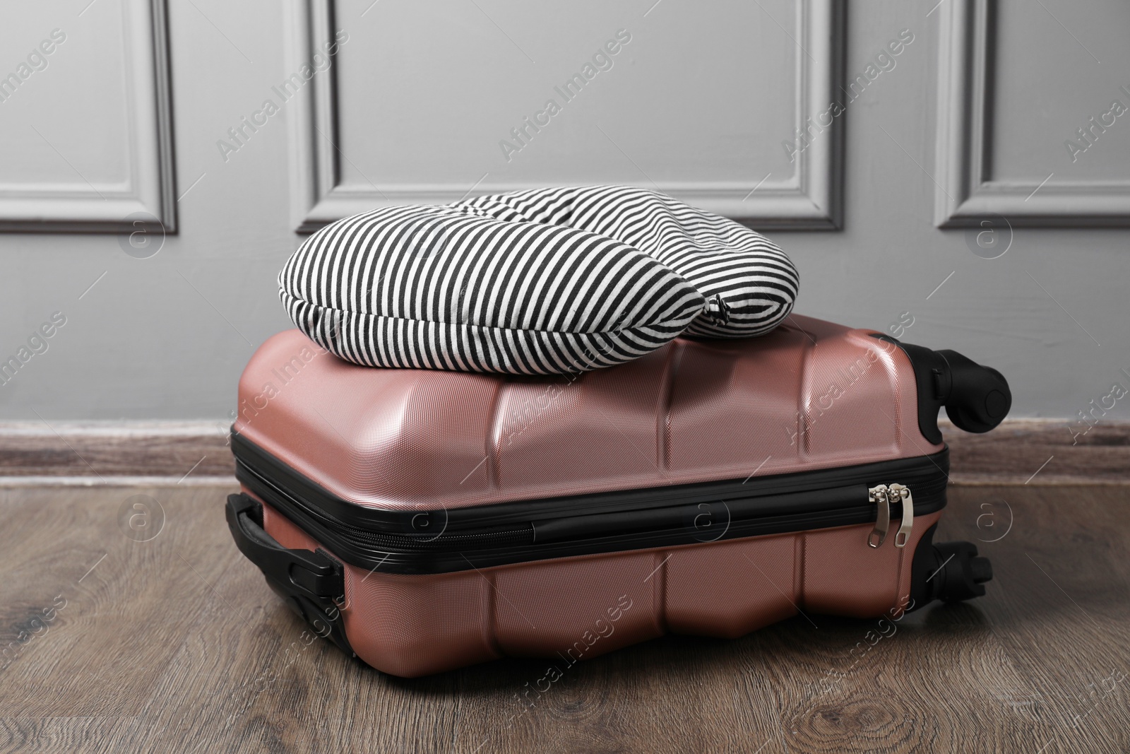 Photo of Striped travel pillow and suitcase on floor