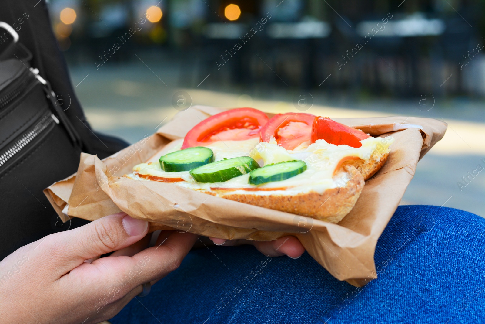 Photo of Woman holding tasty sandwich with vegetables outdoors, closeup. Street food